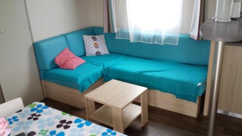 um sofá azul num pequeno quarto com uma mesa em Bungalow de 3 chambres avec piscine partagee jardin et wifi a Louannec em Louannec