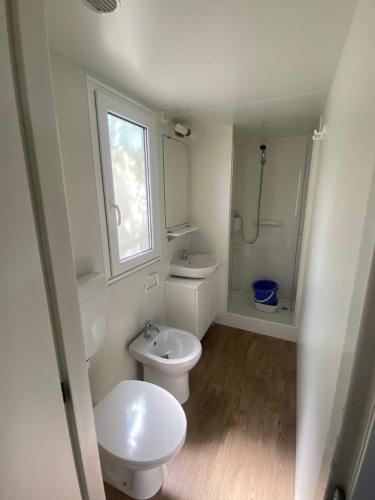a bathroom with two toilets and a sink and a window at Mobilhomes SKALLA CZ in Martinsicuro