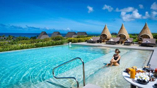 a woman sitting in a swimming pool at a resort at InterContinental Fiji Golf Resort & Spa, an IHG Hotel in Natadola