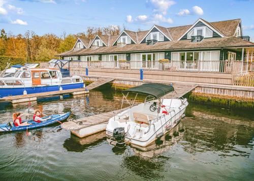 two boats docked at a dock in front of a house at Yare View Holiday Cottages in Brundall