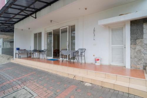a white house with chairs and a table on a patio at Mroom Residence near UMN Gading Serpong RedPartner in Tjitjajur-hilir