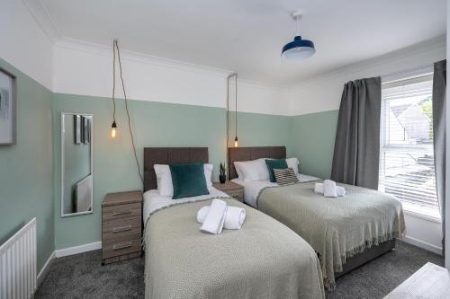two beds in a room with green walls at Stay at the Marine House - TV in every bedroom! in Morriston