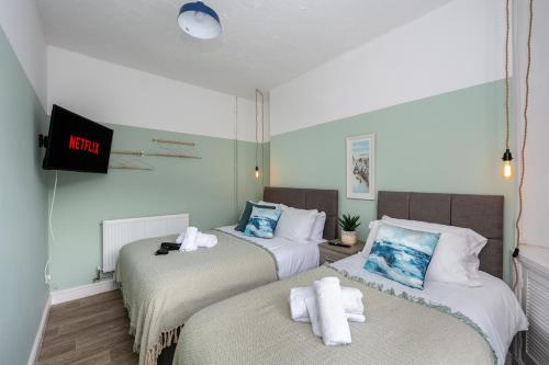 Dos camas en una habitación con un televisor en la pared. en Parking - 2 Baths - Garden - Dining Area, en Swansea