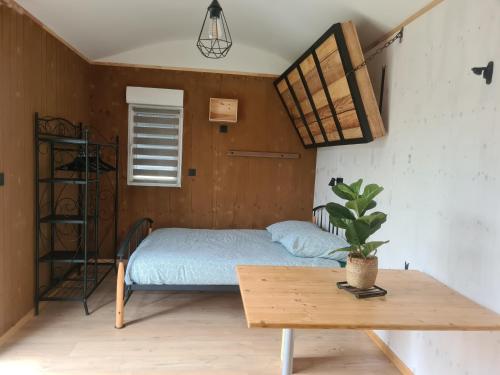 een kleine slaapkamer met een bed en een tafel bij Les Milles Bottes et ses Roulottes in Encausse-les-Thermes