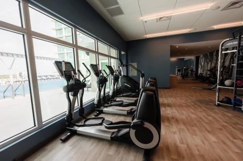 a gym with treadmills and ellipticals in a room with windows at AC Hotel by Marriott Fort Lauderdale Airport in Dania Beach