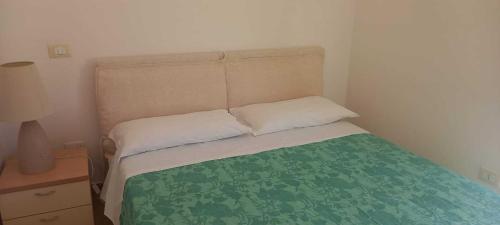 a small bedroom with a bed with a green blanket at Villetta Maria in Botricello