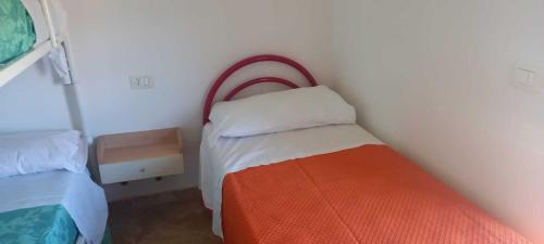 a small bedroom with a bed with an orange blanket at Villetta Maria in Botricello