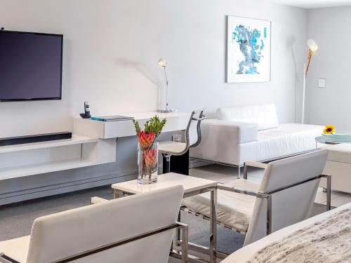 a living room with white furniture and a flat screen tv at South Beach Camps Bay Boutique Hotel in Cape Town
