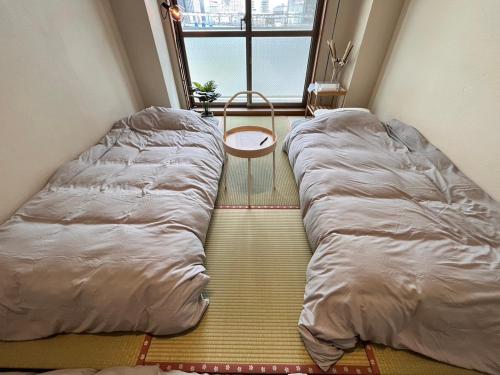 Bett in einem kleinen Zimmer mit Fenster in der Unterkunft 東横のヨコ in Okayama