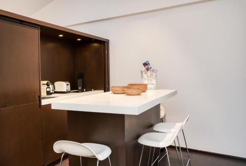 une cuisine avec un comptoir avec des tabourets de comptoir blancs dans l'établissement Appartement Place des lices avec Parking, à Saint-Tropez
