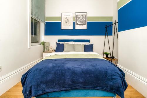1 dormitorio con paredes azules y blancas y 1 cama en Cosy Retreat - Charming 2-Bed Apartment, en Greenock