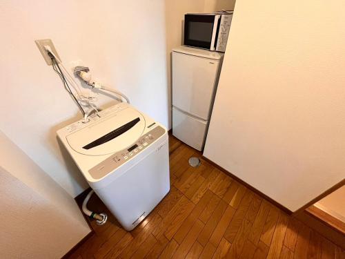 a small kitchen with a refrigerator and a microwave at 東横のヨコ in Okayama