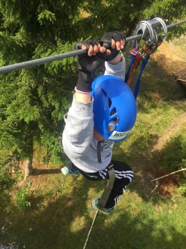 a young boy is hanging on a zip line at In the middle of Trysil fjellet - Welcome Center - Apartment with 4 bedrooms and sauna - By bike arena and ski lift in Trysil
