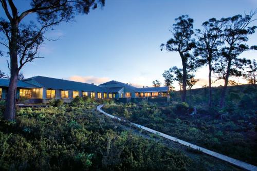 a building in the middle of a field with trees at Cradle Mountain Hotel in Cradle Mountain