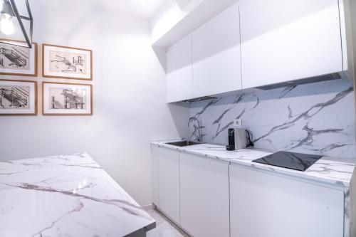 una cocina con armarios blancos y encimeras de mármol en Estudio Elena - Centro, en Torremolinos