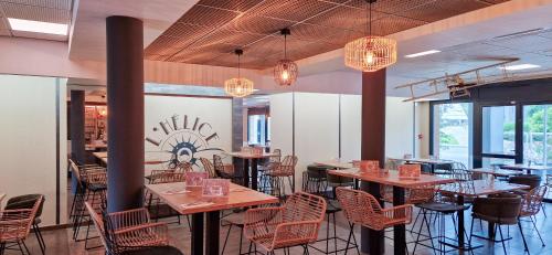 a dining room with tables and chairs and chandeliers at Clarion Aparthotel Toulouse Blagnac Airport in Blagnac
