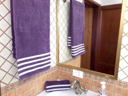 a bathroom with purple towels and a mirror and a sink at 2 bedrooms villa with sea view private pool and furnished terrace at Puntagorda in Puntagorda