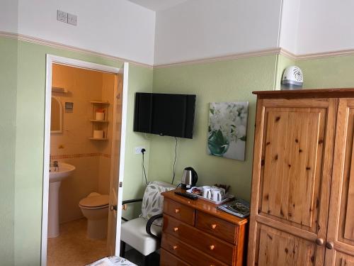 a bathroom with a toilet and a television on the wall at B&B Near the Sea in Paignton