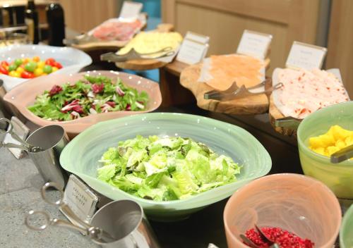 a table topped with bowls of vegetables and other foods at Oriental Hotel Fukuoka Hakata Station in Fukuoka