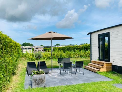 een patio met een tafel en stoelen en een parasol bij Chalet Rivendell in Menaldum