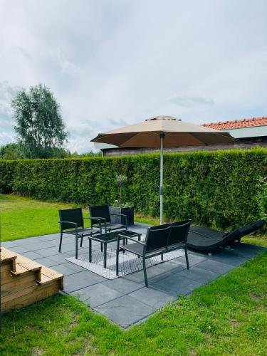 a patio with a table and chairs and an umbrella at Chalet Rivendell in Menaldum