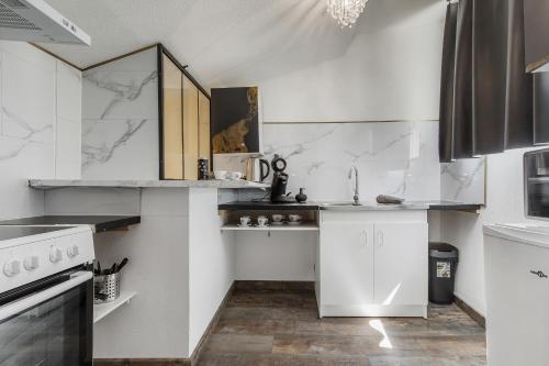 - une cuisine avec des appareils électroménagers blancs et des murs en marbre dans l'établissement COCONROOM balneo-sauna La suitE, à Valros