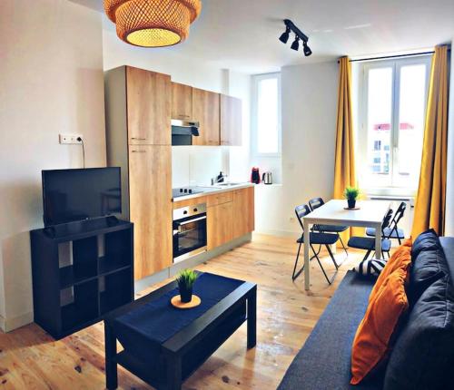 un salon avec un canapé et une table et une cuisine dans l'établissement Charmant DUPLEX à 2 pas du centre de Bayonne, à Bayonne