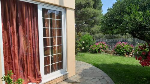 a window with a red curtain next to a yard at PARADISE in Dhaskalión