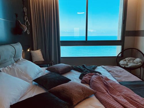 a bed with pillows on it in a room with a window at C Tower Premium Apartments, Panoramic Sea View in Netanya