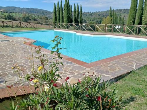 une grande piscine entourée d'une passerelle en pierre dans l'établissement Casa di campagna in Podere con piscina, à Torrita di Siena