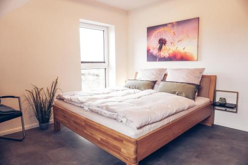 una camera da letto con un grande letto con lenzuola bianche di Ferienwohnung Sonnenaufgangsgenuss Harriersand a Schwanewede
