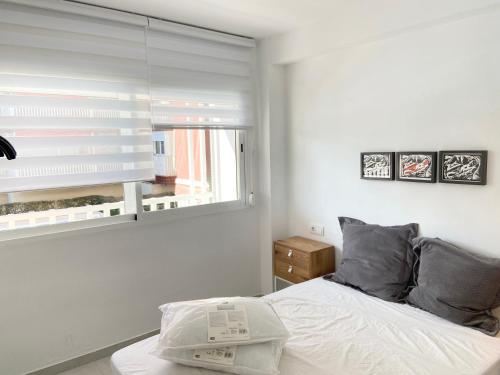 um quarto branco com uma cama e uma janela em Apartamento en la Playa con WiFi rápido, piscina y SmartTV em La Pobla de Farnals