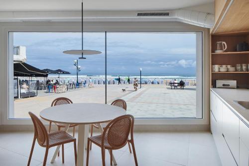 a kitchen with a table and chairs and a view of the beach at Kein Hostel in Zarautz