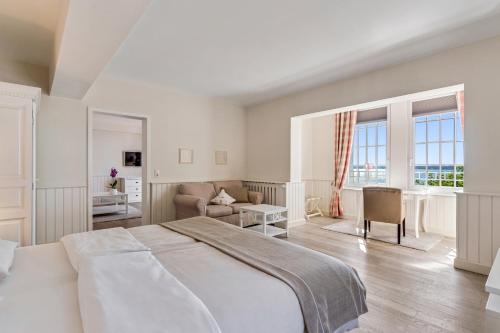 a white bedroom with a large bed and a living room at Strandhotel Glücksburg in Glücksburg