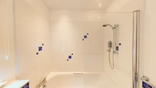 uma casa de banho branca com um chuveiro e uma banheira em Druim An Lochain Cottage em Kinrara