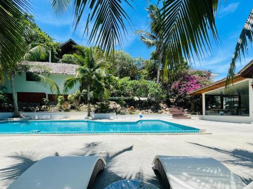 een zwembad met palmbomen en een huis bij Tantawan sea view residence 山海居 in Salad Beach