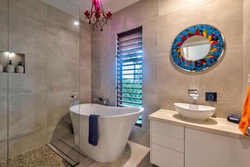 ein Badezimmer mit einer Badewanne, einem Waschbecken und einem Spiegel in der Unterkunft Heliconia 10 Newly Renovated Centrally Located House Hamilton Island in Hamilton Island