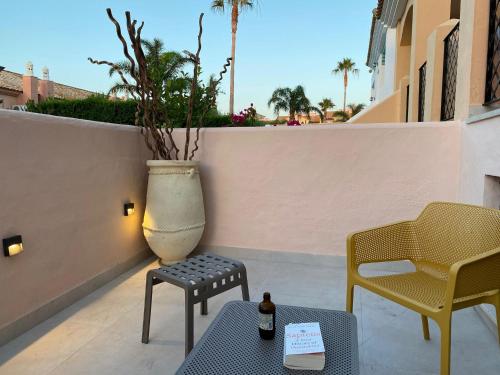 eine Terrasse mit 2 Stühlen und einem Tisch mit einer Flasche Bier in der Unterkunft BRISA DE ZAHARA - Casa para familia con piscina y garaje en Urb. privada in Zahara de los Atunes