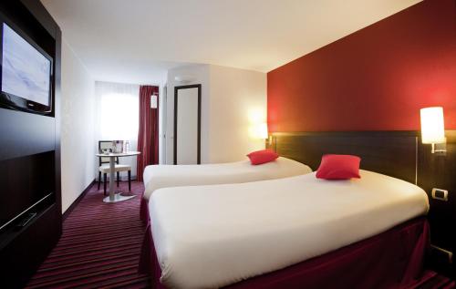 um quarto de hotel com duas camas e uma televisão de ecrã plano em ibis Styles Belfort Centre em Belfort