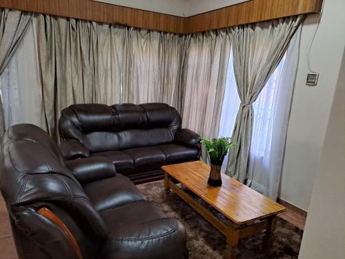 a living room with a leather couch and a coffee table at Courtlyguesthouse in Witbank
