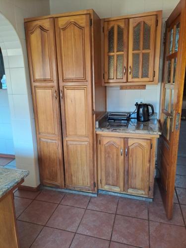 a kitchen with wooden cabinets and a tea kettle at Courtlyguesthouse in Witbank