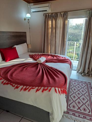 um quarto com uma cama com um cobertor vermelho em Courtlyguesthouse em Witbank