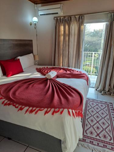 a bedroom with a bed with a red blanket on it at Courtlyguesthouse in Witbank