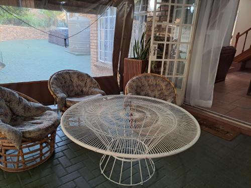 a white table and chairs and a table and chairs at Courtlyguesthouse in Witbank