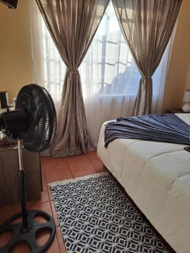 a bedroom with a fan in front of a window at Courtlyguesthouse in Witbank