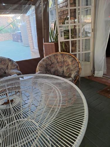 a large white table with chairs and a large fan at Courtlyguesthouse in eMalahleni