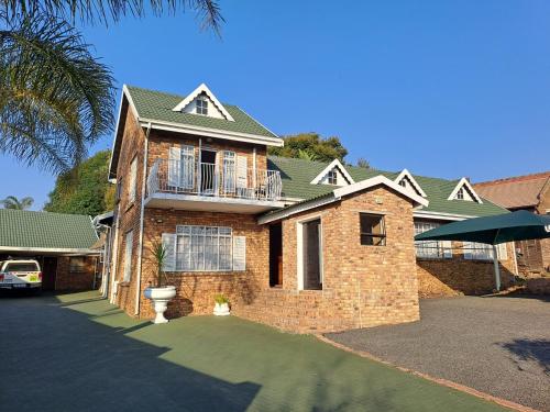 a large brick house with a balcony on it at Courtlyguesthouse in Witbank