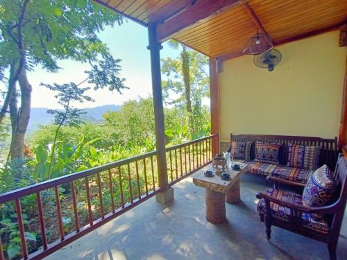 a porch with a couch and a table on a balcony at Puluong Home in Pu Luong