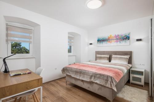 a white bedroom with a bed and a desk at Apartment City Peace in Rijeka