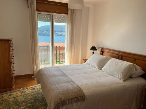 a bedroom with a bed and a large window at VENTANAMAR CHAPELA in Redondela